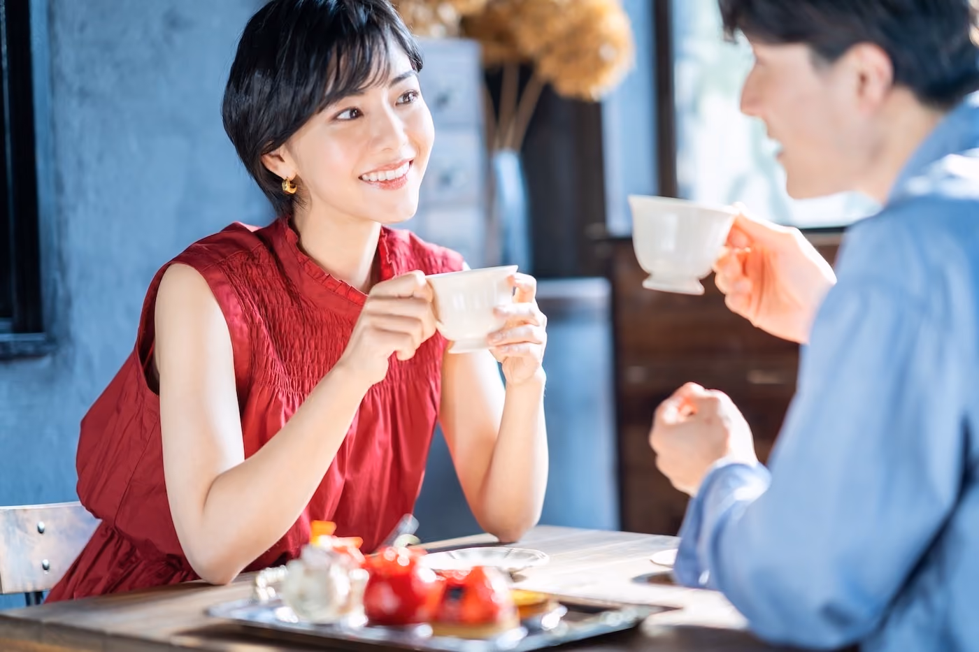 赤いドレスを着た魅力的な女性とお茶を飲む男性